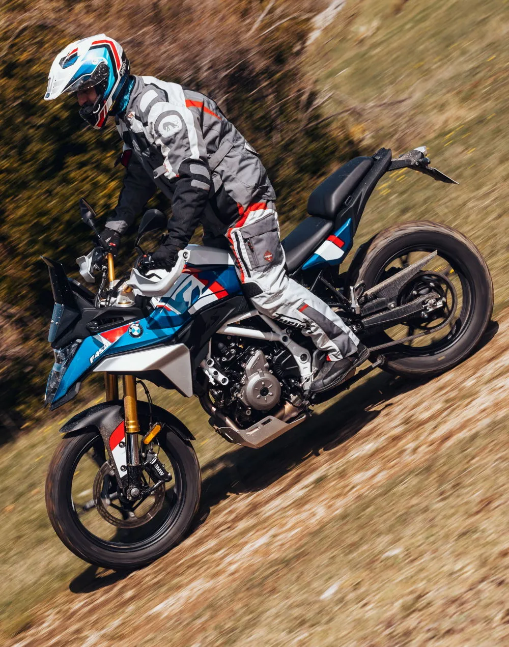 Une BMW F 450 GS bleu blanc et rouge dans un environnement tout terrain