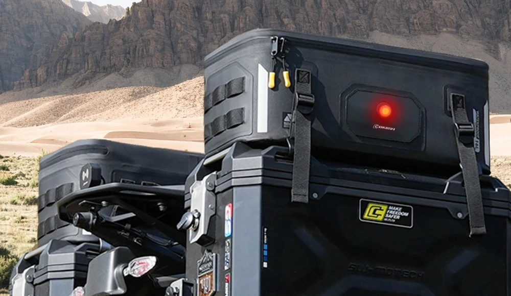 Une sur-valise Cokima sur une valise de moto en métal et un paysage montagneux aride
