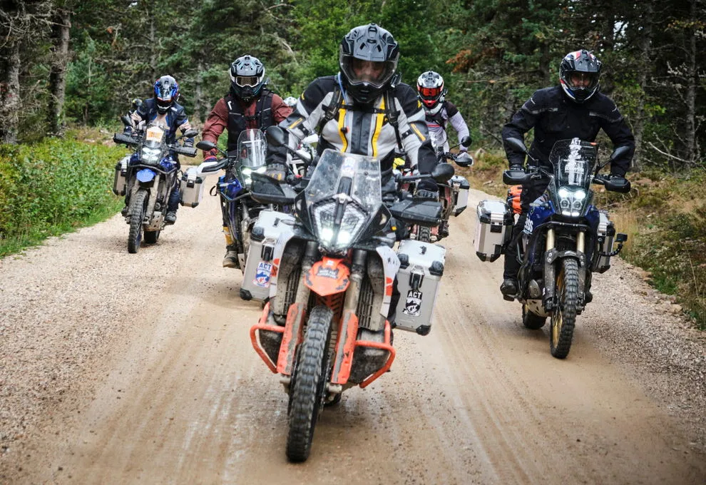 Un groupe de motos type trail sur route en terre dans une foret