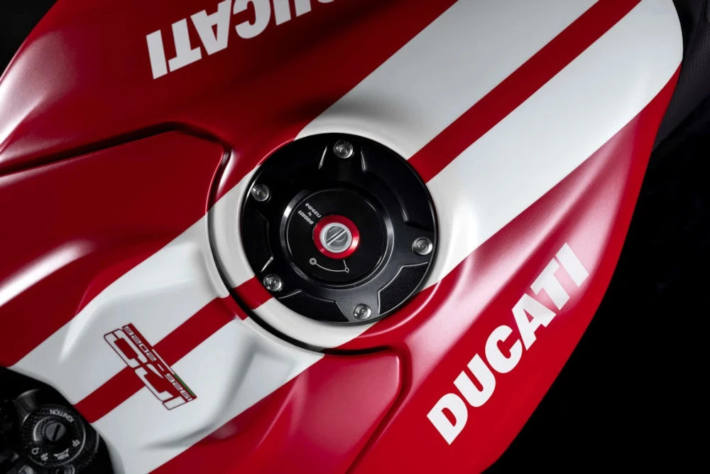 Gros plan sur le logo rouge Ducati apposé sur le réservoir d'une moto sportive haut de gamme.