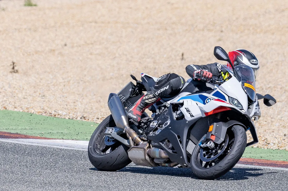 Une BMW S 1000 RR 2026 blanche sur circuit, une bande verte et du gravier