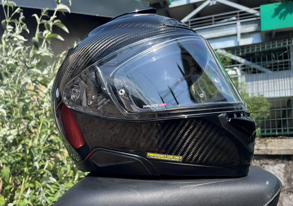 Un casque HJC Rpha 72, des feuilles d'arbre et un grillage