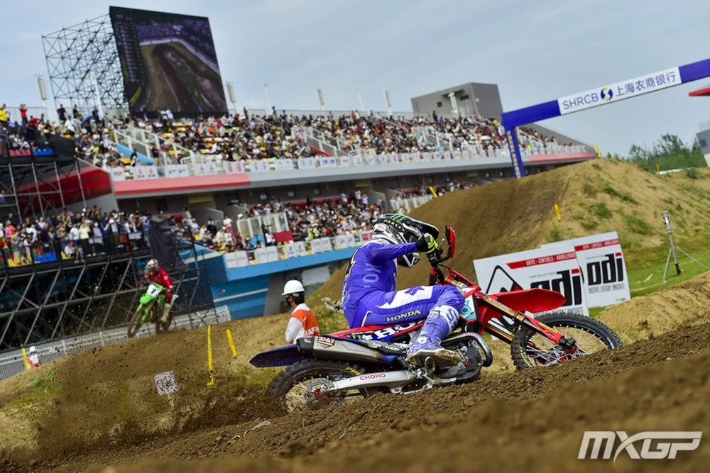 Jeffey Herlings avec ta tenue violette et sa Honda rouge, dans un virage. On aperçoit Febvre au loin