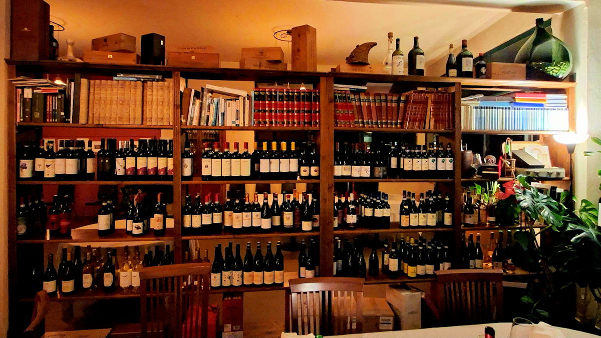 Una estantería con libros y botellas de vino