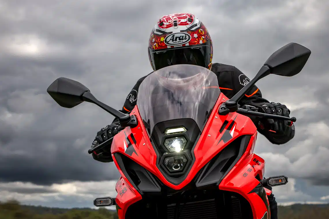 L'avant rouge d'une Suzuki GSX-8R 800 Edition Anniversaire, un casque de moto Arai et un ciel nuageux