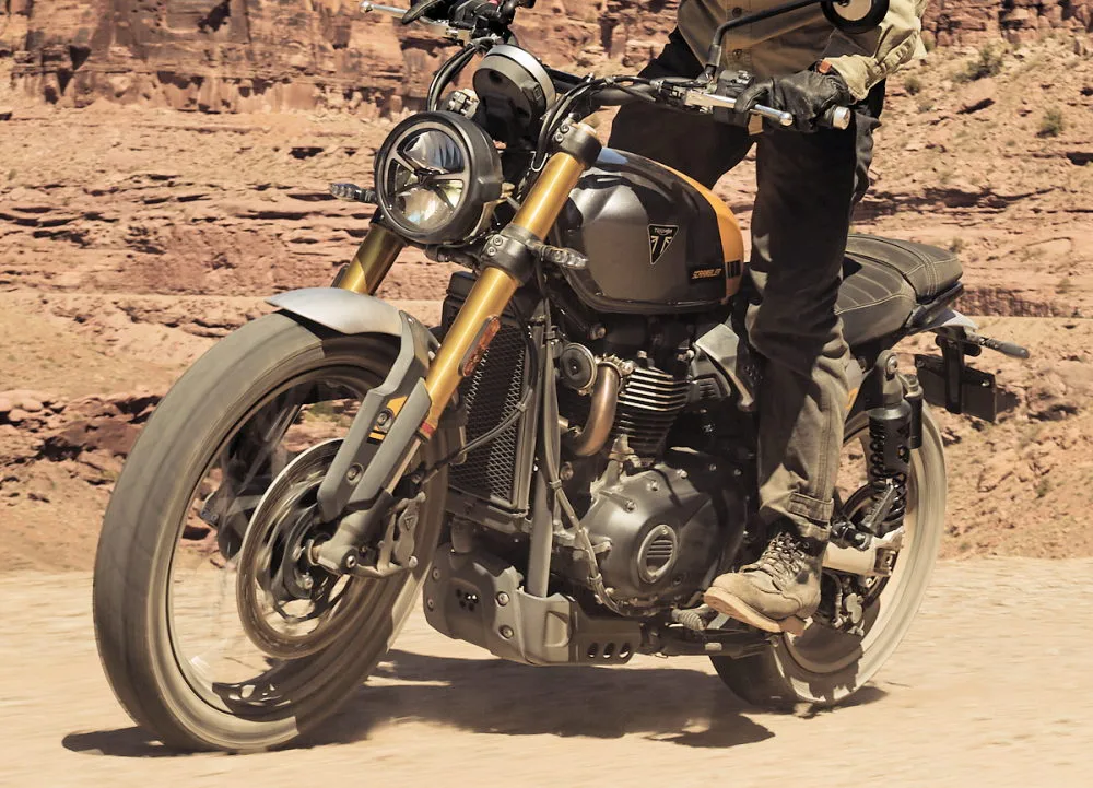 Une Triumph 900 Scrambler 2026 roulant sur une route aride